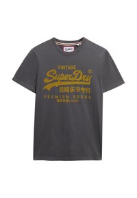 Graues T-Shirt mit kurzen Ärmeln aus Baumwolle, mit goldbedrucktem Text: "VINTAGE SuperDry" und zusätzlichen Markierungen in verschiedenen Sprachen.