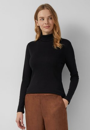 Zwarte coltrui van zachte stof met lange mouwen, gecombineerd met bruine, suède-achtige high-waisted broek. Gladde textuur, aansluitend ontwerp.