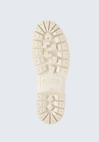 Beige rubberen buitenzool met een gestructureerd oppervlak, voorzien van verschillende geometrische patronen en diepe groeven voor grip. Gemarkeerd met merk en maat.