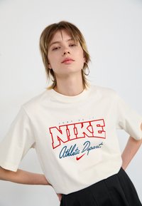 Witte katoen T-shirt met rode en blauwe grafische tekst "JUST DO IT" en "NIKE Athletic Dept." Korte mouwen en ronde halsontwerp.