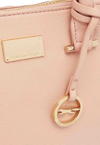 Zachte roze leren tas met gouden ritssluiting, rechthoekig naambordje en ronde gouden charme met een silhouette van een rennende greyhound.