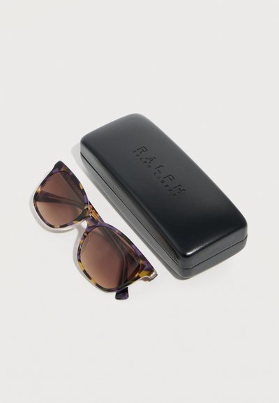 Γυαλιά ηλίου με κορνίζα από όστρακο χελώνας και καφέ φακούς δίπλα σε κλειστή μαύρη ορθογώνια θήκη Ralph Lauren σε λευκό φόντο.