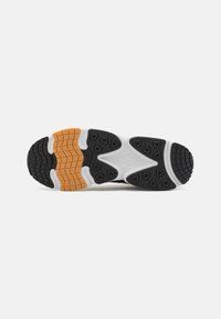 Black and white athletic shoe sole with textured rubber in triangular and hexagonal patterns; features orange and light grey accents.