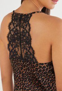 Camisole med leopardprint med sort blondebaggrund. Glat stof, justerbare stropper og detaljeret blonde ved halsudskæringen.