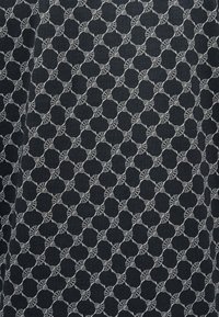 Σκούρο ύφασμα με επαναλαμβανόμενο μοτίβο από ανοιχτόχρωμα αφηρημένα κυκλικά σχήματα, συνδεδεμένα με ριγέ γραμμές που σχηματίζουν σχέδιο πλέγματος.
