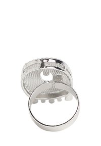 Sølvmetalring med en struktureret bande og et åbent design, der har en cirkulær topsektion med en glat overflade og små accenter.