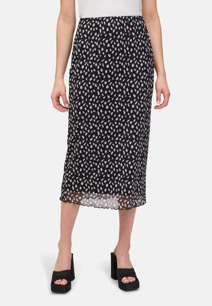Jupe midi noire avec un motif blanc en forme de feuilles, fabriquée en tissu léger. Ourlet festonné, portée avec des sandales plates-formes noires épaisses.