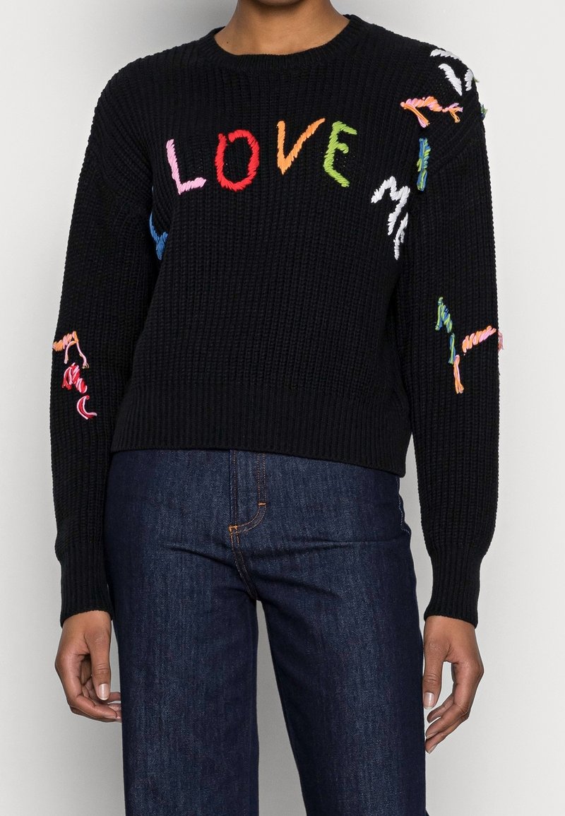 Černý pletený svetr s barevnými vyšitými písmeny tvořícími slovo "LOVE" v různých odstínech. Žebrovaná textura s detailními akcenty na rukávech.