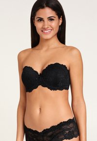 Zwarte kanten strapless beha met gesneden randen en bloemmotieven, voorzien van een strikaccent in het midden en gevoerde cups.