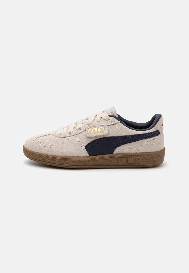 Baskets basses en daim beige Puma avec semelle gomme, bande latérale noire, lacets crème et logo doré « Puma Palermo » sur le côté.