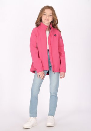 Jachetă roz cu fermoar și guler înalt, cu o textură moale. Dispune de un logo brodat cu umbrelă, fiind asortată cu blugi bleu deschis și adidași albi.