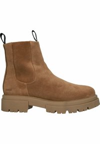 Bota de ante marrón hasta el tobillo con suela de goma gruesa y tira de agarre. Presenta una textura suave y paneles laterales elásticos. Branding sutil en el lateral.