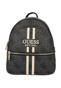 Sac à dos en toile noir avec des rayures beiges, logo "GUESS EST 1981", motif texturé, et poche frontale zippée avec quincaillerie métallique.