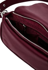 Borsa in pelle bordeaux con cerniere argentate. L'interno è foderato in tessuto coordinato con diversi scomparti per l'organizzazione.