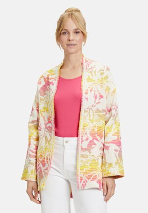 Blomsterkort cardigan i hvid, pink og gul med en løs pasform, tekstureret stof, åben front og brede ærmer, båret over en pink top.