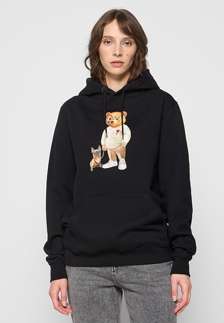 Hoodie noir avec un personnage d'ours portant un sweat-shirt blanc et tenant un chien marron. Comprend une poche avant et un capuchon avec cordon.