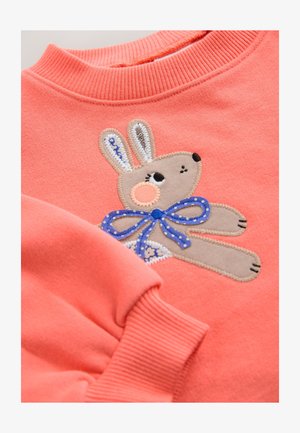 Korálová mikina s žebrovaným výstřihem, s vyšívaným motivem králíka s modrou puntíkovanou mašlí a světle hnědými detaily.