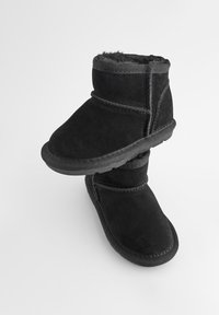 Bottines noires en daim doux avec un intérieur moelleux. Dotées de coutures contrastantes et de semelles en caoutchouc, conçues pour le confort.