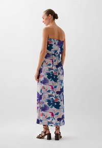 Maxi dress featuring a vibrant, abstract print in shades of purple, blue, and pink. Strapless design with gathered waist and flowy fabric.