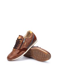 Sneaker in pelle e camoscio marrone con accenti blu e gialli a contrasto, allacciatura frontale e zip laterale. Suola in gomma con motivi testurizzati.