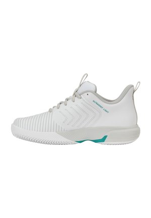 Witte sportschoen met een gestructureerde zool, chevronpatronen aan de zijkant, grijze veters en turquoise accenten met het label "Ultrashot Light" op het hielgedeelte.