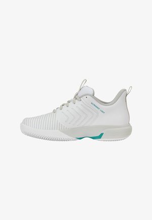 Chaussure de sport blanche avec semelle texturée, motifs en chevrons sur le côté, lacets gris et accents bleu sarcelle étiquetés "Ultrashot Light" sur la zone du talon.