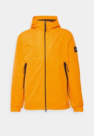 Veste légère orange vif avec capuche, dotée d'une fermeture éclair à l'avant et de poches zippées sur les côtés, complétée par des accents et des détails noirs.