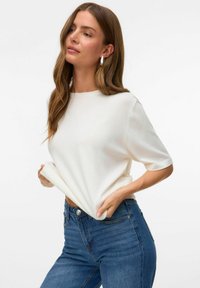 Hvid, kortærmet, crew-neck top lavet af blødt stof, parret med højtaljede blå jeans. Glat tekstur, minimalistisk design.