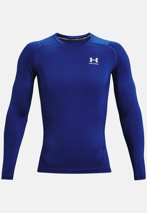 Langærmet træningsshirt i lys blå stof med rund halsudskæring, tætsiddende pasform og hvidt logo på brystet. Glat tekstur.
