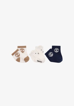 Drie paar babysokjes in wit en bruin, wit met berengezichten en marineblauw met boomlogo’s, naast elkaar gerangschikt op een witte achtergrond.