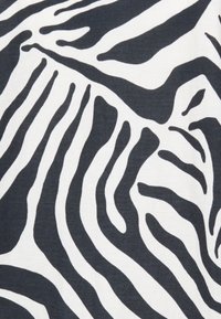 Motif zèbre en noir et blanc avec des rayures ondulées et audacieuses sur un tissu texturé. Le design présente des largeurs variées et des courbes fluides.