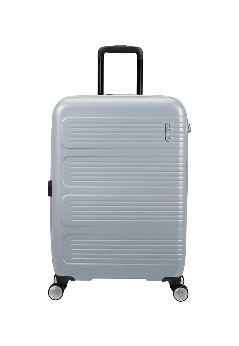 Maleta rígida en gris claro con un diseño acanalado texturizado, manija retráctil negra y cuatro ruedas giratorias para una fácil movilidad.