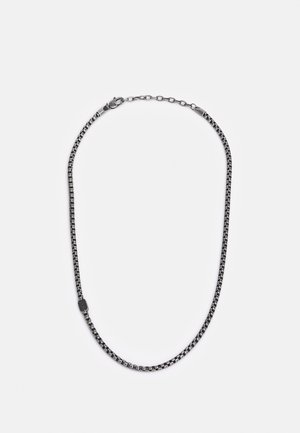 Collier chaîne à maillons carrés ton argent avec fermoir mousqueton réglable et courte chaînette d’extension sur fond blanc.