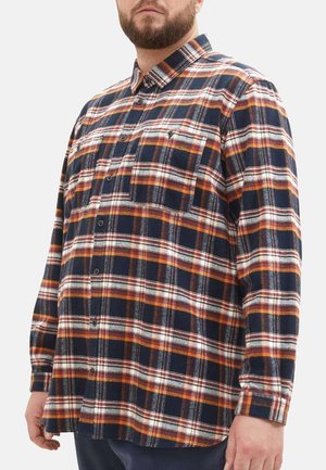 Chemise en flanelle à manches longues, à carreaux bleus, oranges et blancs, avec fermeture à boutons et une poche sur la poitrine. Tissu texturé avec un design traditionnel.