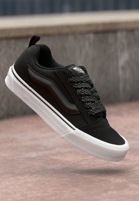 Svart sneakers med teksturert overdel, med prikkete snører, hvit såle og side-stripe detaljer. Designet for uformell bruk.