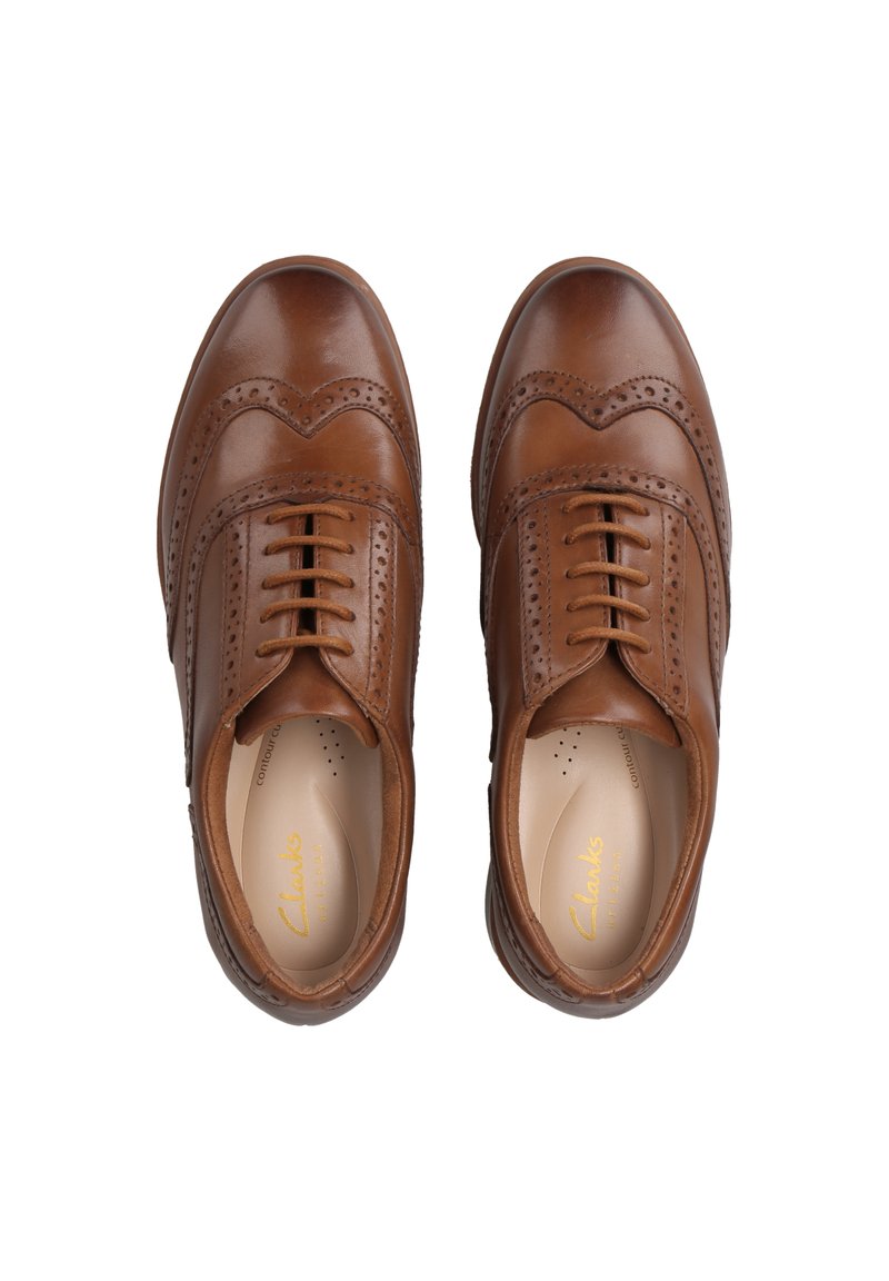Zapatos de piel marrón con detalles de brogue, diseño de cordones, punta redondeada y textura suave. Presentan una plantilla acolchada y un sutil logotipo en el interior.