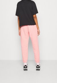 Svart t-shirt med kort ärm, i kombination med rosa, uppvikta joggers. Skorna är svarta och vita sneakers med rosa detaljer.