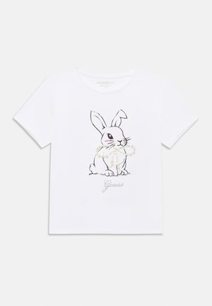 Tricou alb din bumbac cu contur negru al unui iepure și accente cu perle. "Guess" este imprimat cu argintiu sub grafică. Mâneci scurte.