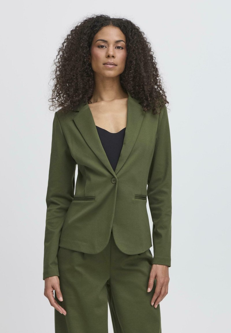 Blazer verde oliva realizzato in tessuto morbido, con chiusura a un bottone, silhouette leggermente sfiancata e tasche anteriori per un tocco di dettaglio.