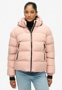 Roze pufferjack met een ritssluiting aan de voorkant, een verstelbare capuchon en zwarte ritssluiterzakken. Heeft gestikte panelen en ribgebreide manchetten.