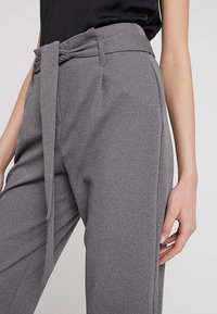 Grijze hoge taillebroek met een strikriem, gemaakt van een structuurstof, met zijzakken en een losse pasvorm.