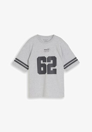 Hellgraues übergroßes T-Shirt mit schwarzen doppelten Armbändern, "BROOKLYN NYC" Text über der großen schwarzen Zahl "62" auf der Vorderseite.