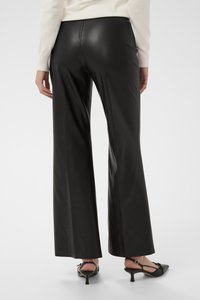 Melnas ādas zvana bikses ar spīdīgu tekstūru, vidēja augstuma vidukli un nepamanāmas šūšanas detaļas; kombinētas ar melniem slingbeka papēžiem.