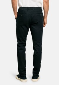 Pantaloni in cotone neri con vestibilità slim, due tasche posteriori con chiusura a bottone e una texture liscia. Presenta un cinturino con passanti.