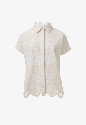 Camisa de manga corta con cuello en color crema claro, que presenta un intrincado bordado y detalles de dobladillo en forma de ondas. Tela texturizada con un diseño estampado.