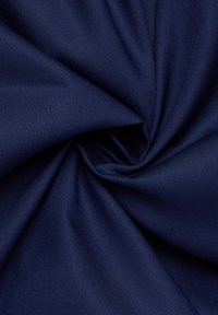 Tessuto blu navy con una texture liscia, disposto in una spirale, che mostra un motivo di tessitura uniforme e un colore consistente in tutta la superficie.