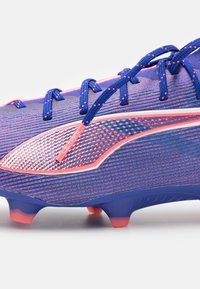 Crampone de football bleu et rose avec une tige synthétique texturée. Caractéristiques des lacets intégrés et un logo proéminent. Studs sur la semelle extérieure pour une traction optimale.