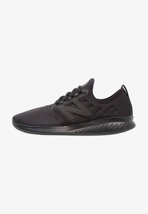 Baskets de sport noires avec dessus en mesh, fermeture à lacets, semelle coussinée et logo de marque sur le côté.
