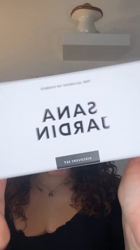 Białe pudełko z czarnym napisem "SANA JARDIN" i "DISCOVERY SET." Tekst jest pogrubiony i nowoczesny. Pudełko ma gładkie wykończenie.