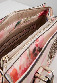 Blommönstrad handväska i nyanser av rosa och beige, med dragkedjestängning, satininteriör och metalliska detaljer.